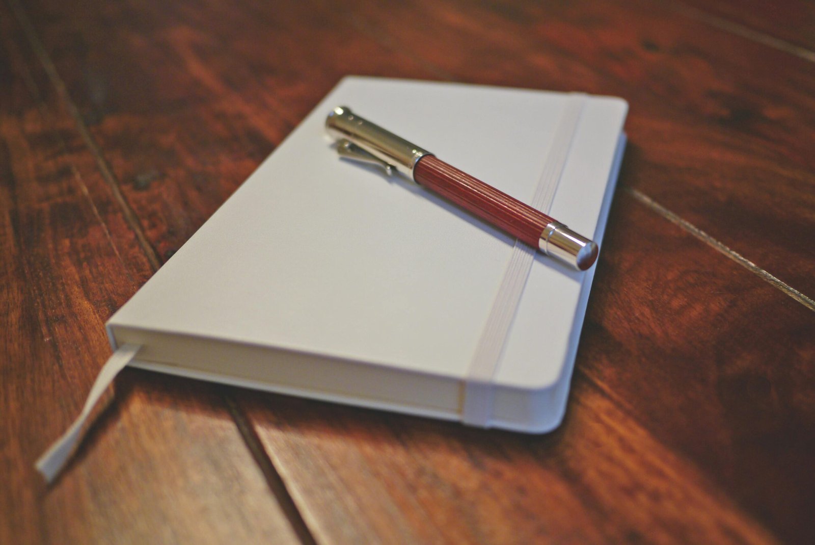 Elegant setup of a notebook and pen on a wooden desk, capturing a minimalist stationery arrangement.
